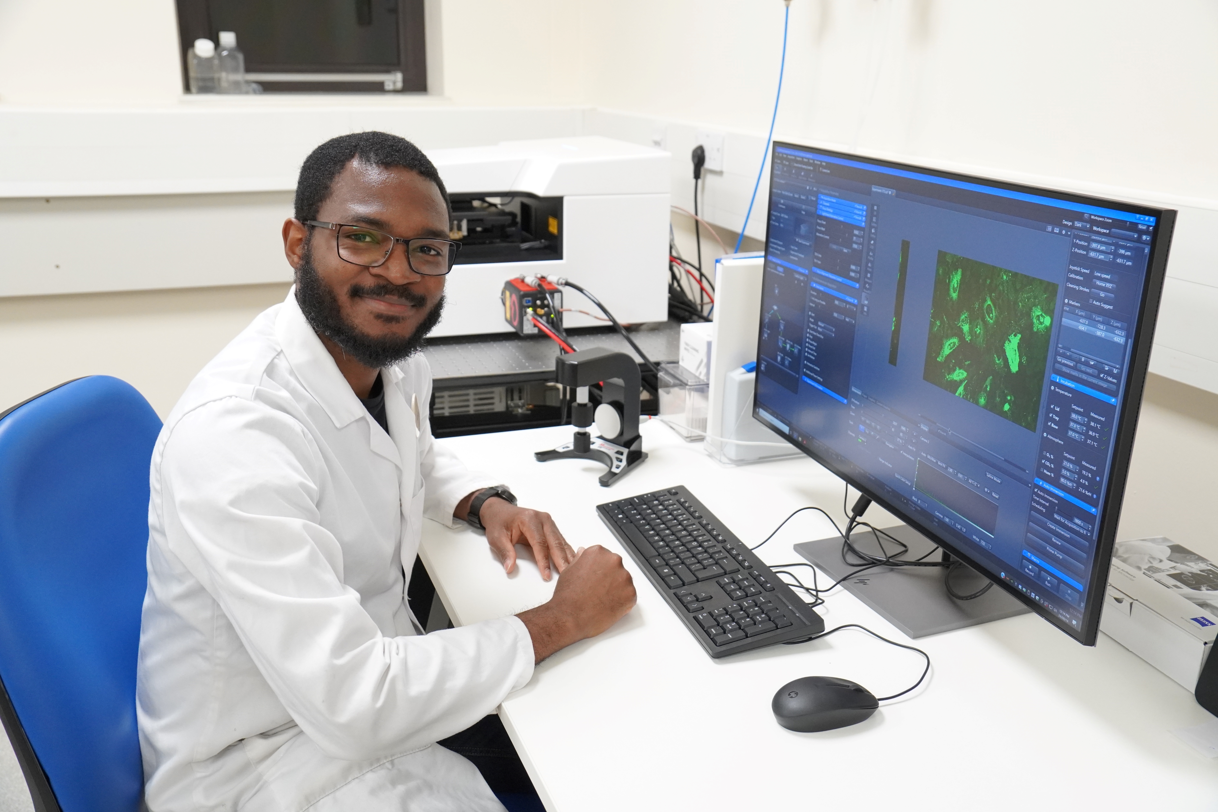 Post doctoral student sitting by lattice lightsheet microscope and computer to control it