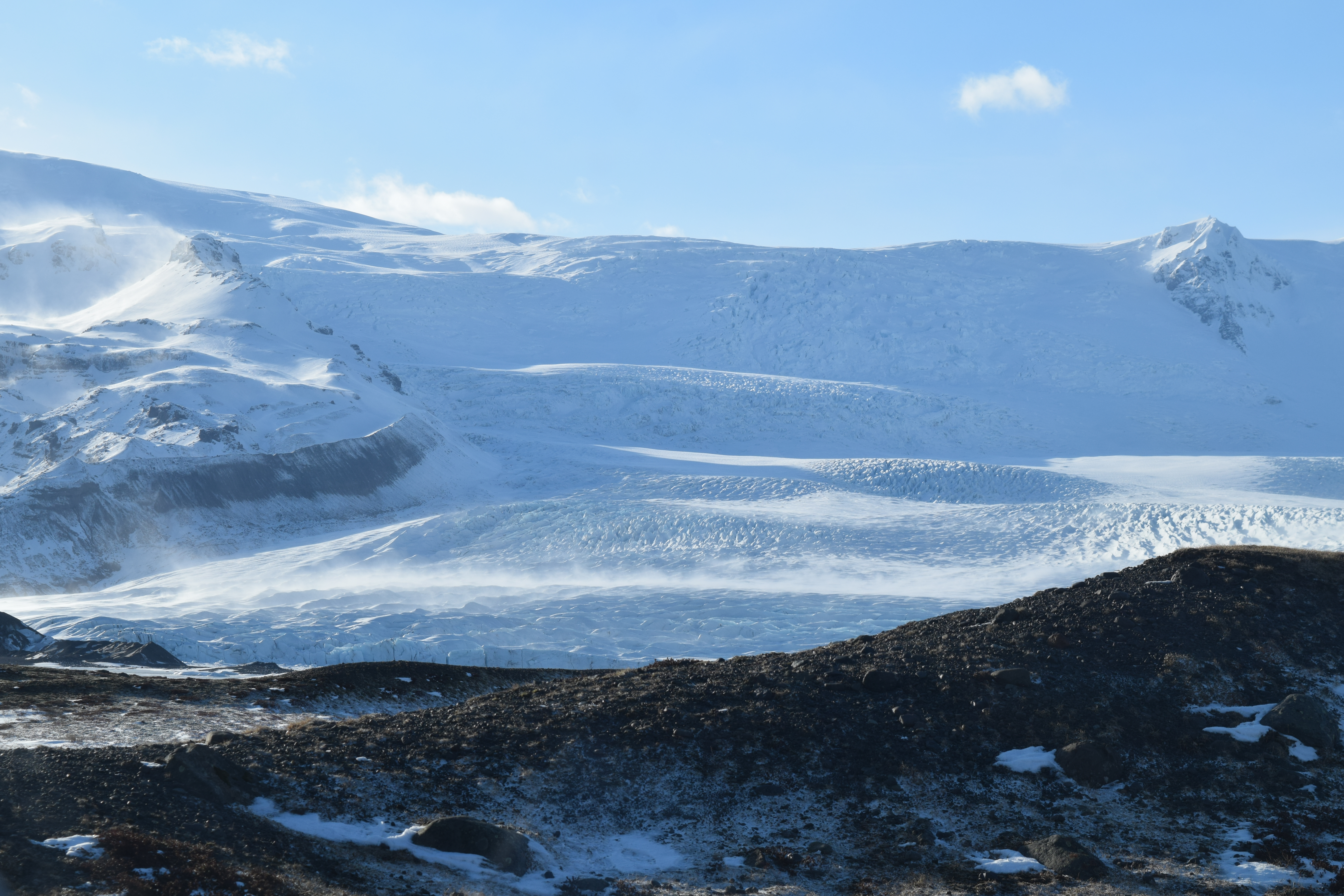 snow drifting off of a arctic mountain