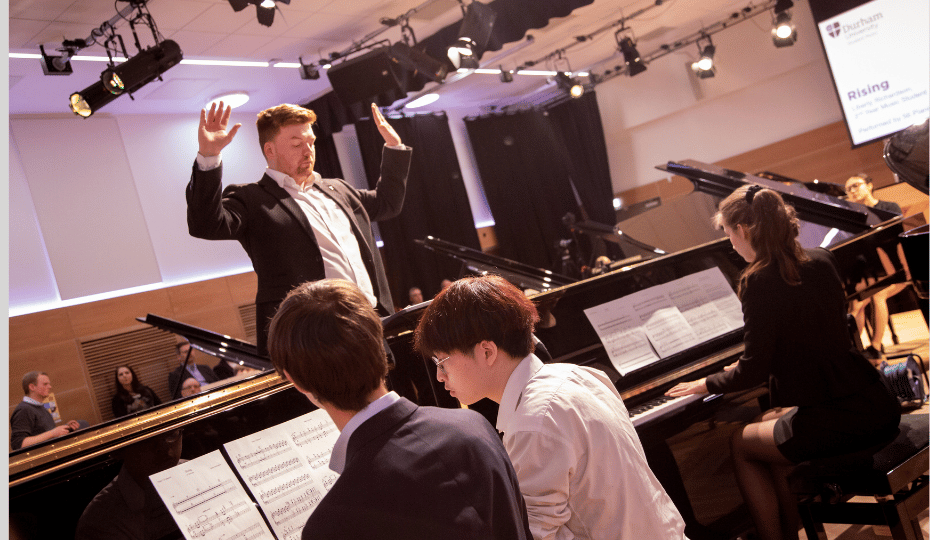 Students playing Steinway pianos with a conductor