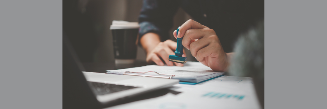 A hand stamping a document on a desk