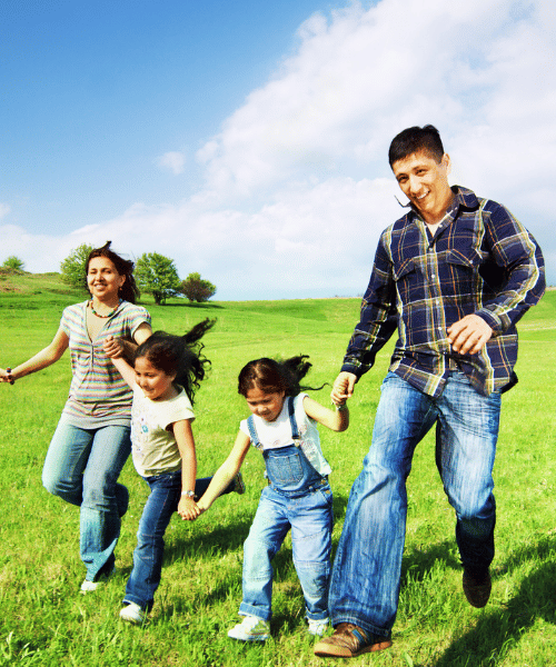 A family with two young children walking hand in hand in a field