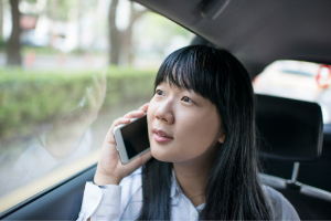 An East Asian woman talks on the phone while in her car