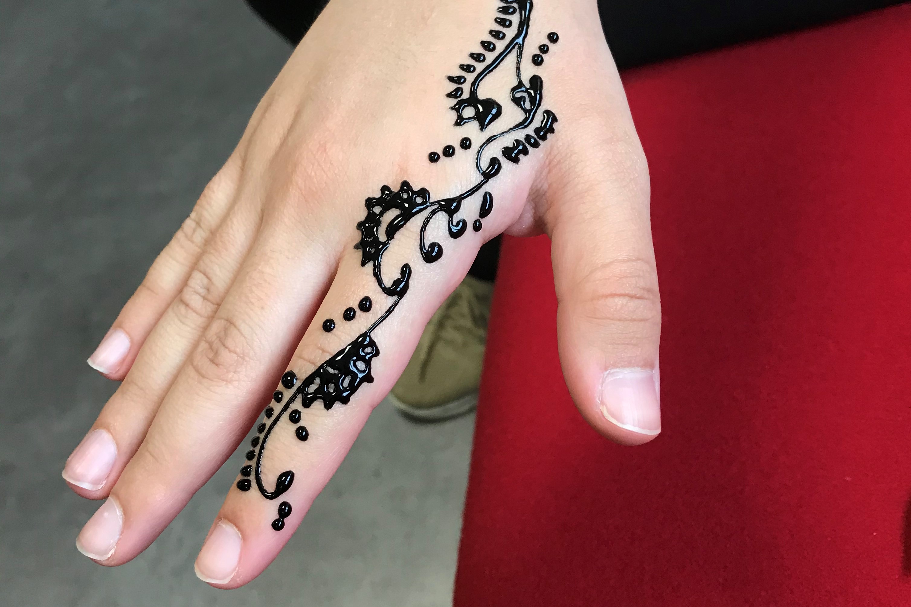 A student's hand featuring a Henna design