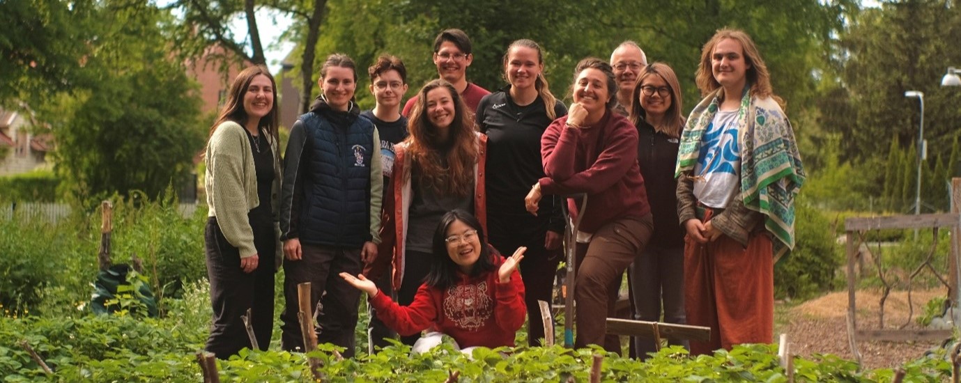 A group of smiling students posing for a group photo, surrounded by trees