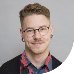 A man with short brown hair and glasses smiling at the camera.