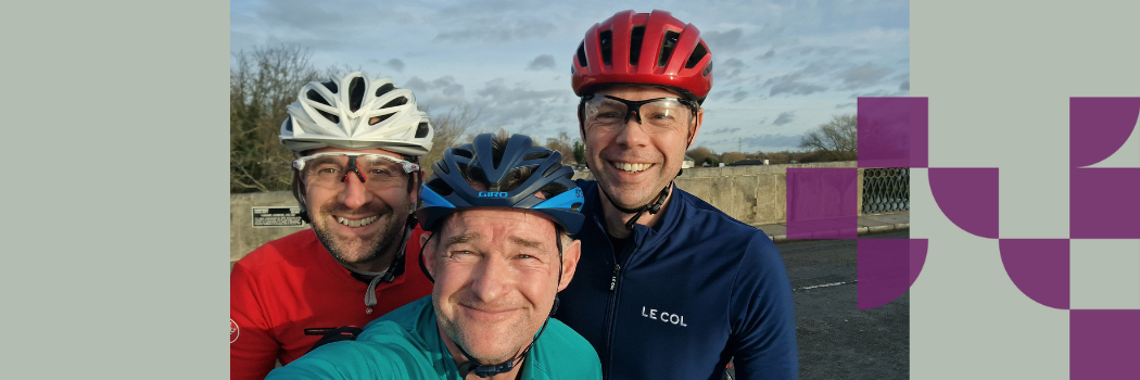 Three men wearing cyling gear smiling at the camera