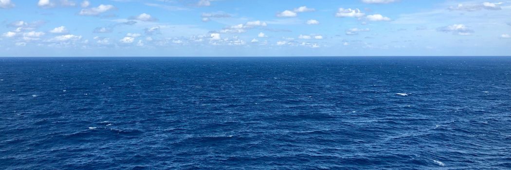 A picture of the northern Atlantic showing dark blue sea with a light blue sky and small white clouds.