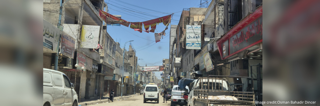 Image of a street in Raqqa City, Syria, with evidence of damage alongside everyday life