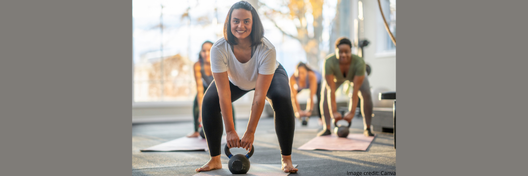 Gym class lifting handheld weights with smiling woman in foreground