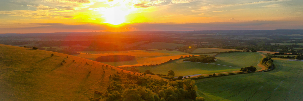 Sun setting over rolling fields of UK countryside