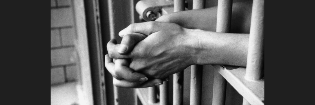 Female hands through prison cell bars