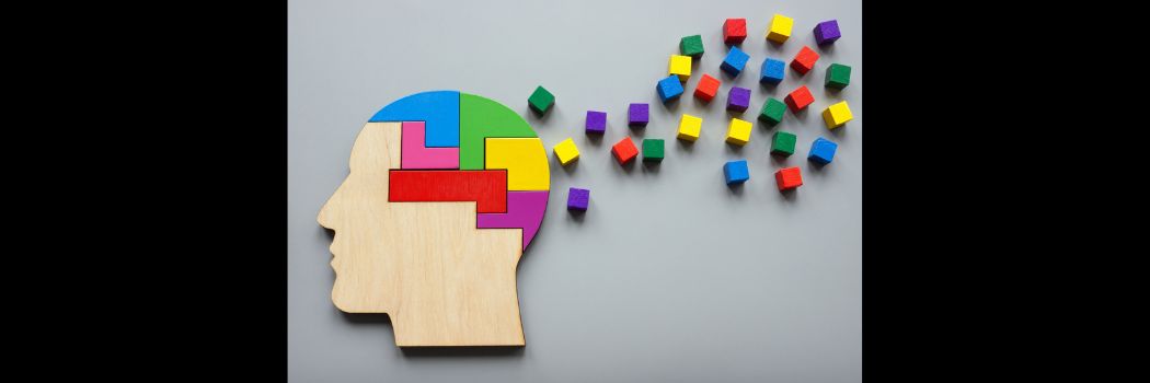 A wooden jigsaw-like picture of a head, with coloured bricks apparently flying away from it