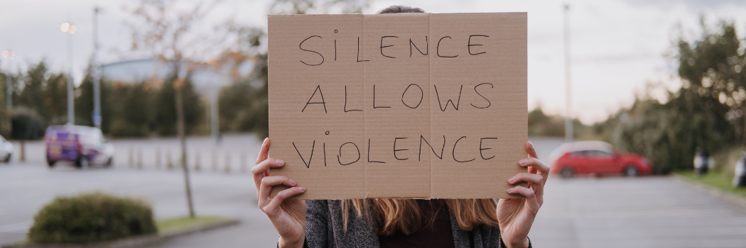 A woman holding a protest sign saying silence is violence
