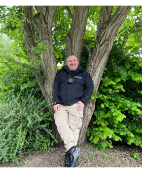 New Biodiversity Manager Ian Armstrong smiling leaning against a tree he planted in the 1990s