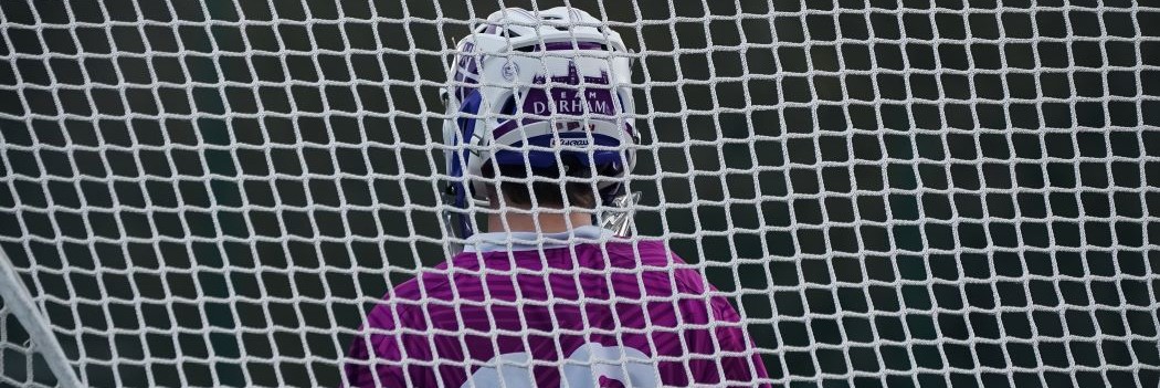 A Team Durham player in full kit seen through the back of a goal