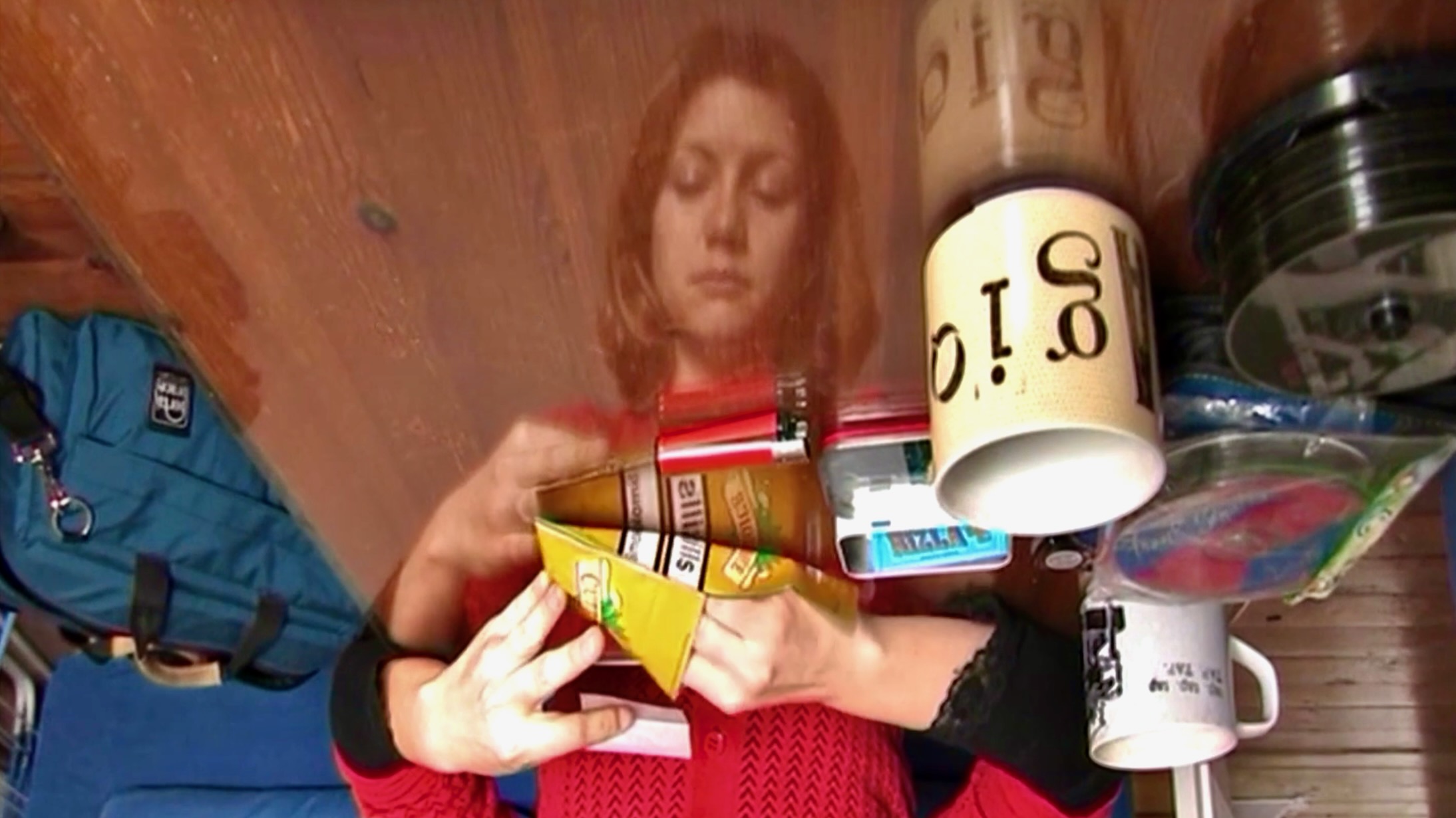 A reflective image from an ethnographic film project showing a participant engaged in the everyday act of rolling tobacco
