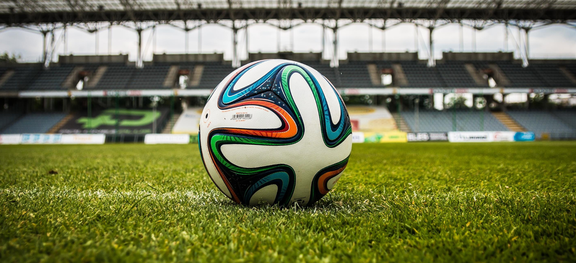 A football on a pitch in the middle of a stadium