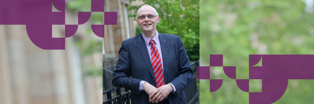 Graham Towl smiling wearing a suit and leaning against railings