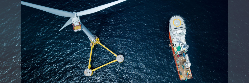Aerial view of a wind turbine and a ship in the sea