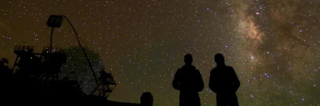 Two people looking up at a dark, starry sky.