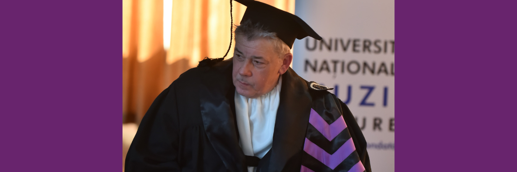 Man in commencement cap and gown giving speech at podium