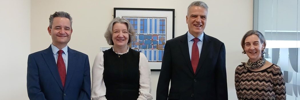 A mixed group of four smartly dressed people standing in a line smiling at the camera