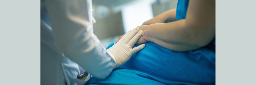 A doctor's gloved hand rests on a patient's arm