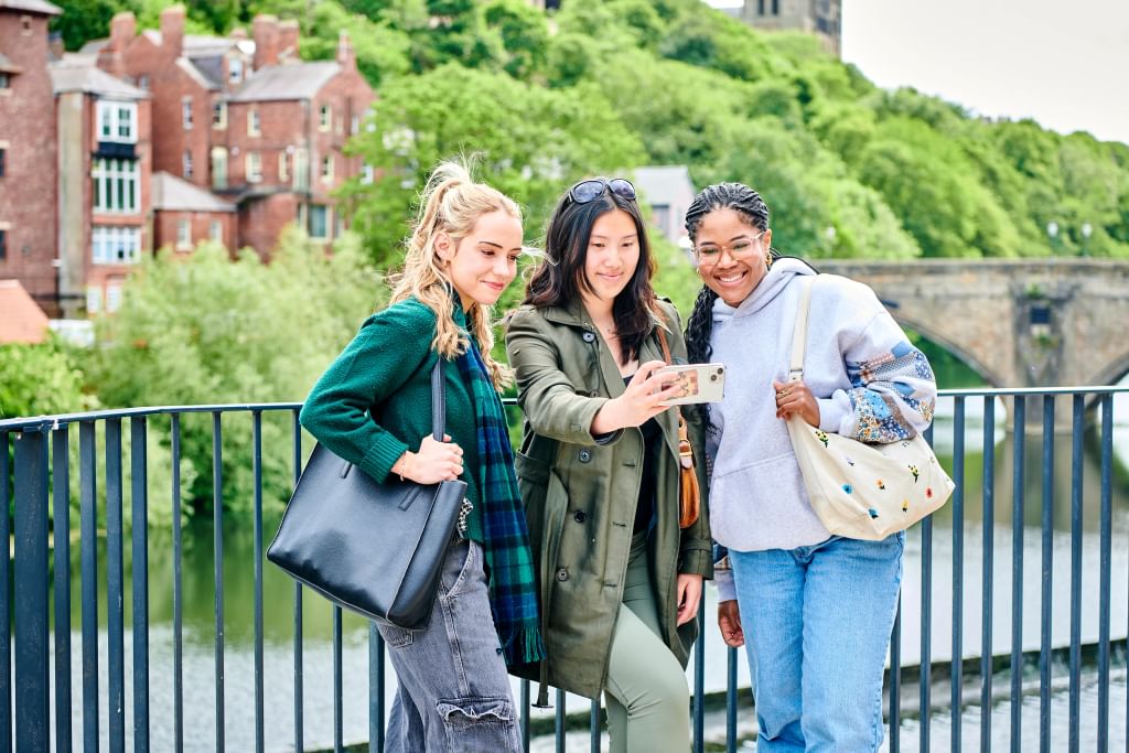 students looking at phone with view of cathedral