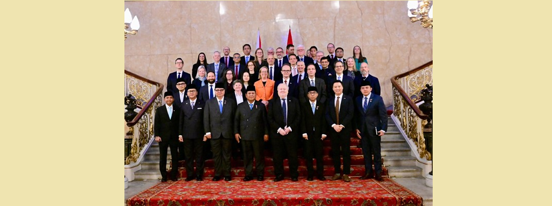 A group of people stand together on stairs, in front of flags