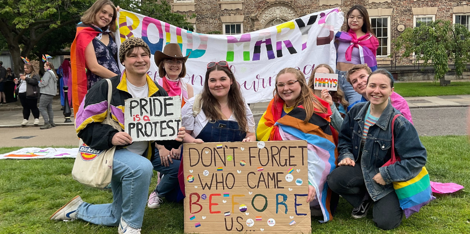 Students in a Pride event on Palace Green in Durham City, holding banners and placards
