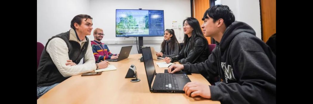 Students with laptops sitting round a shared table