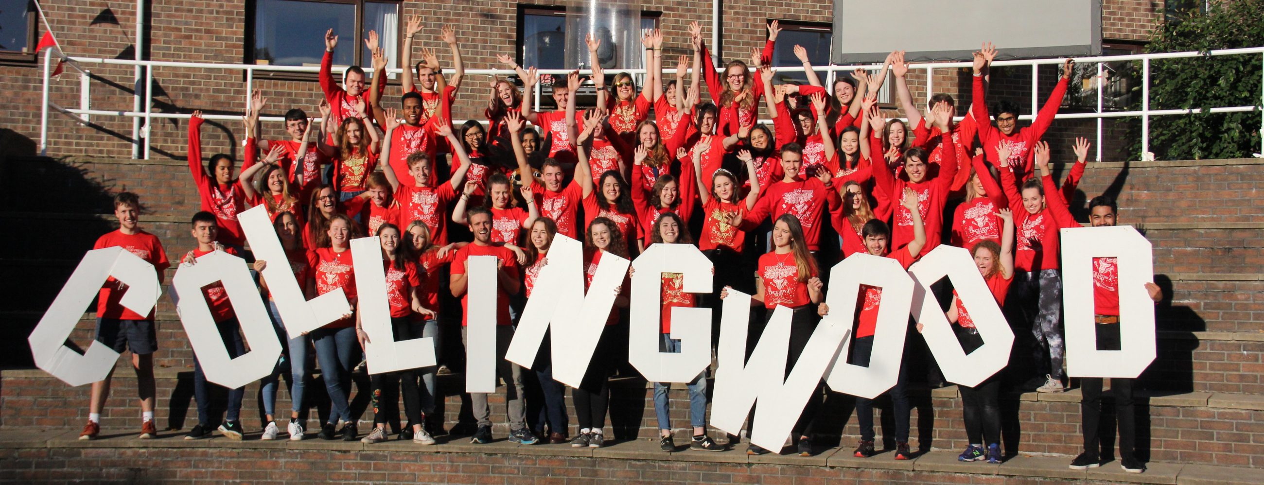 Students in red freshers t-shirts holding Collingwood sign