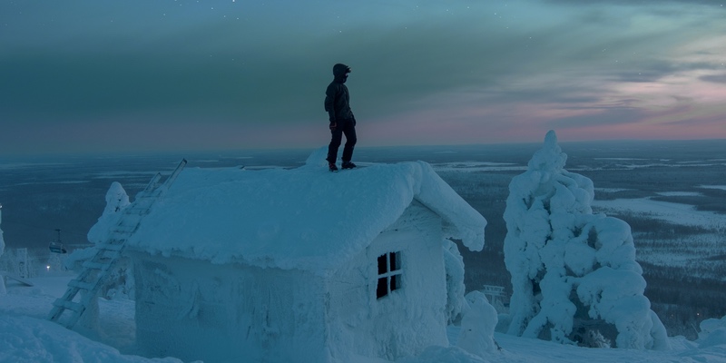 A man standing on a house covered in snow