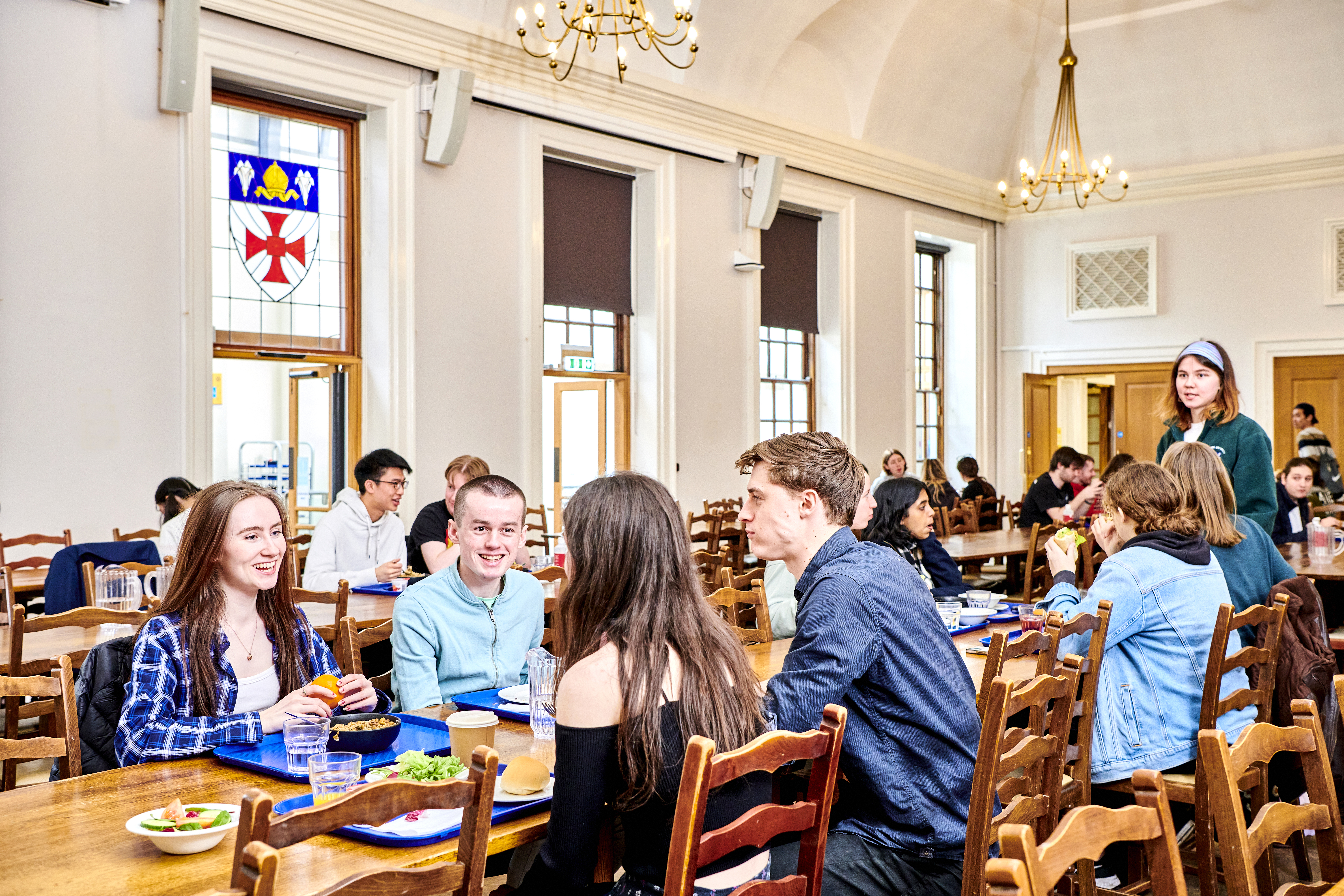 A wide shot of the dining hall with many students enjoying their meals and talking with one another