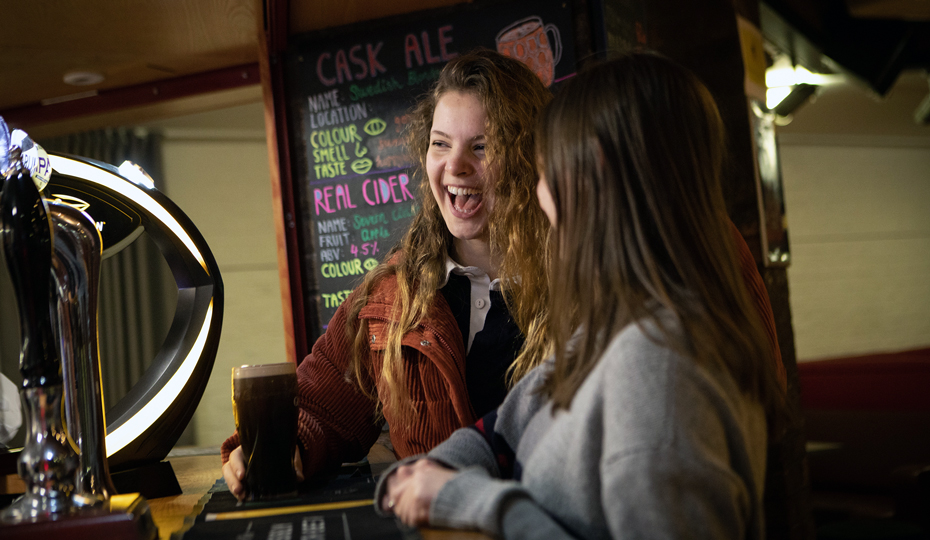 Students laugh and chat over a pint at Trevs Bar