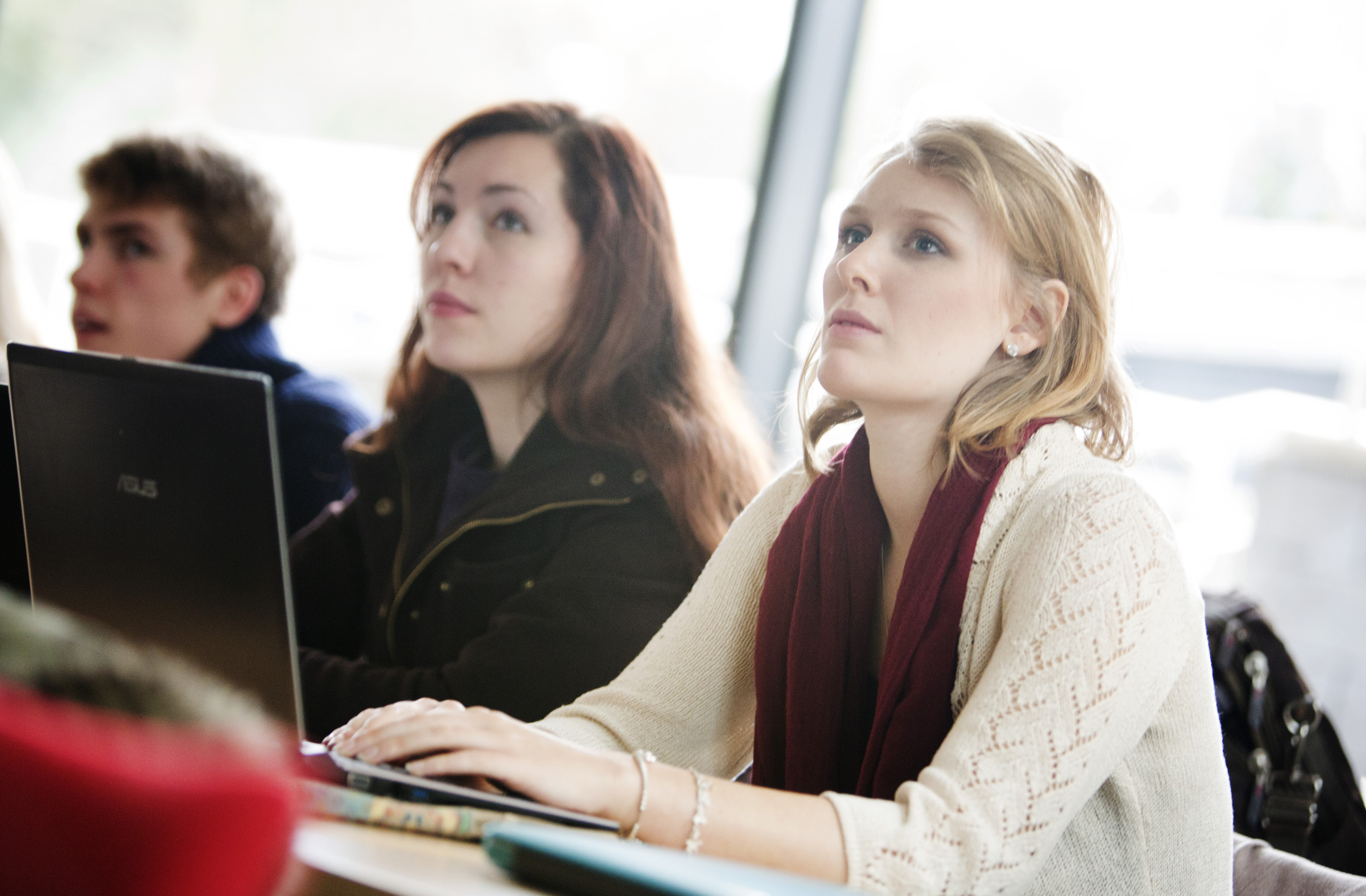 Students on a laptop listening during a lecture