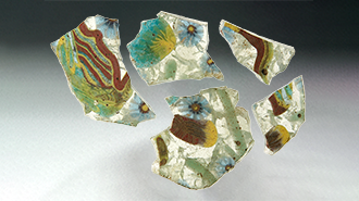 Sherds of polychrome glass on a graded background