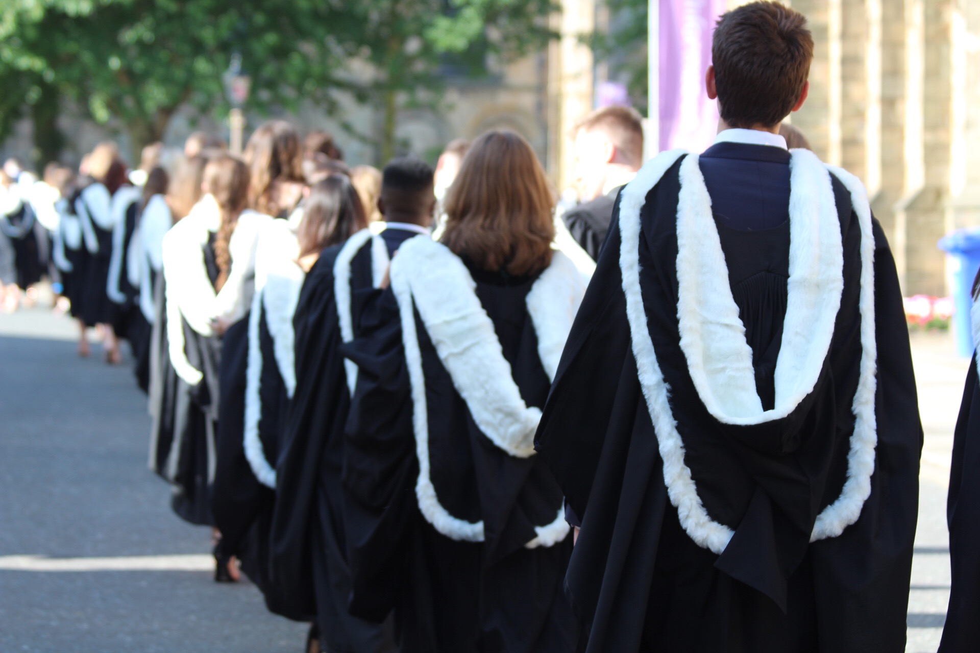 Students walking out of Durham cathedral wearing graduation robes