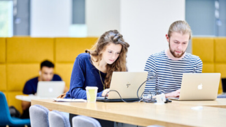 A male and female looking at laptops in our Teaching and Learning Centre.