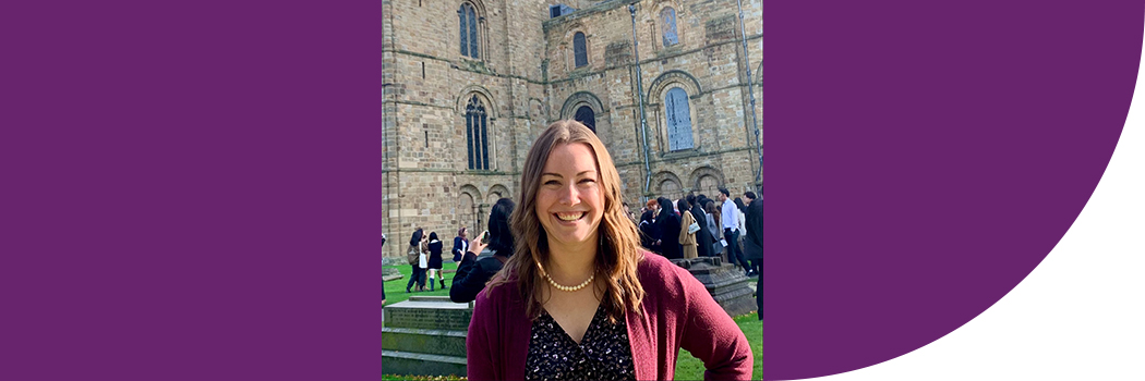 Female student with brown hair, standing in front of cathedral.