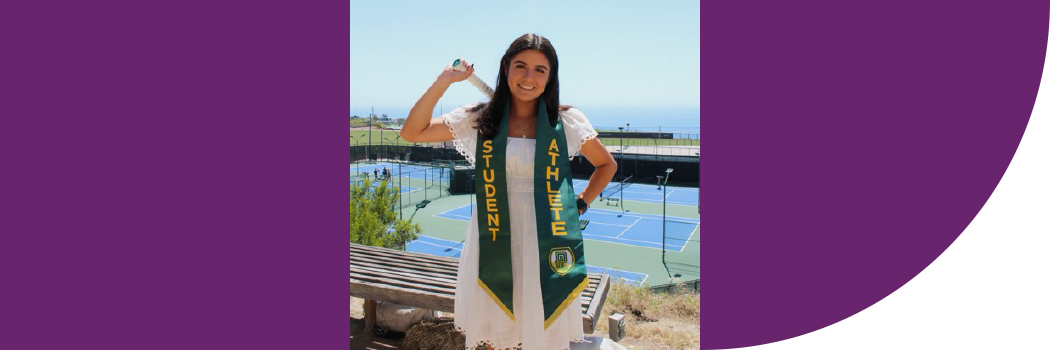 Female student with dark hair, wearing white dress and standing in front of tennis courts.