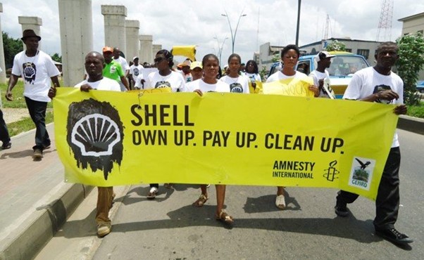 People holding up a banner protesting Shell, saying