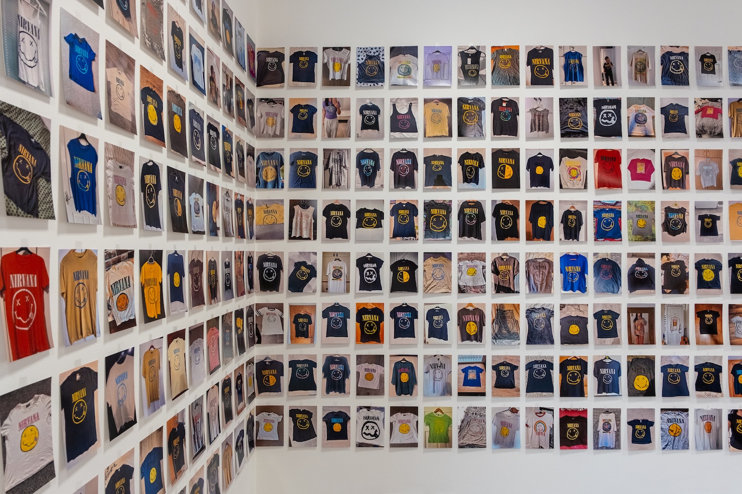 A grid of photographs on a wall, reaching round a corner