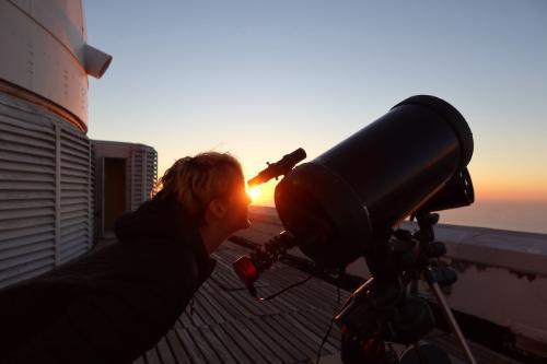 Student aligning telescope at sunset