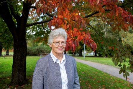 Photo of Anne L'Hullier stood beneath a tree in autumn colours