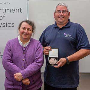 Photograph of Andrew receiving his award, presented by Paula Chadwick.