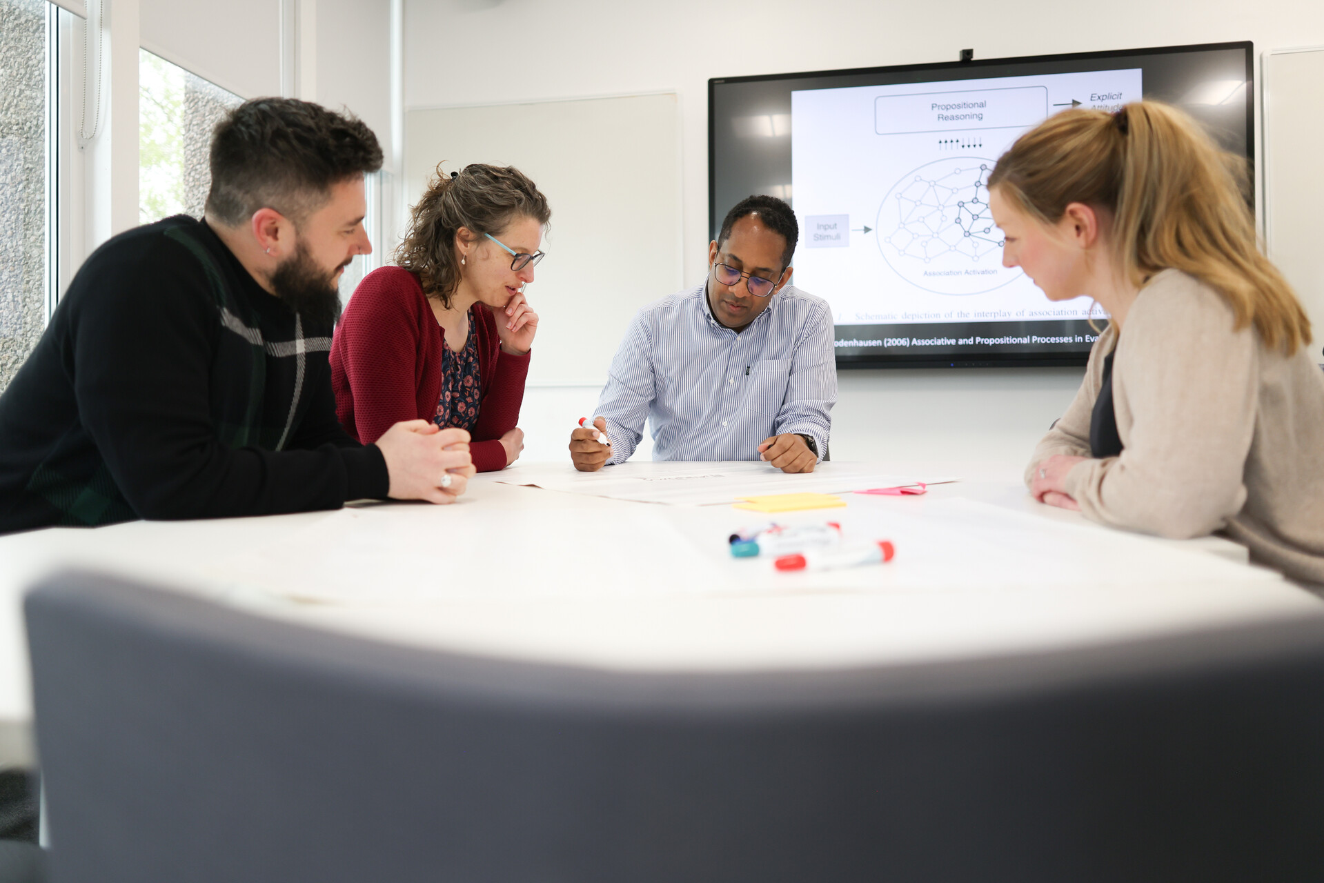 A group of staff members sat around a meeting table looking at a document.