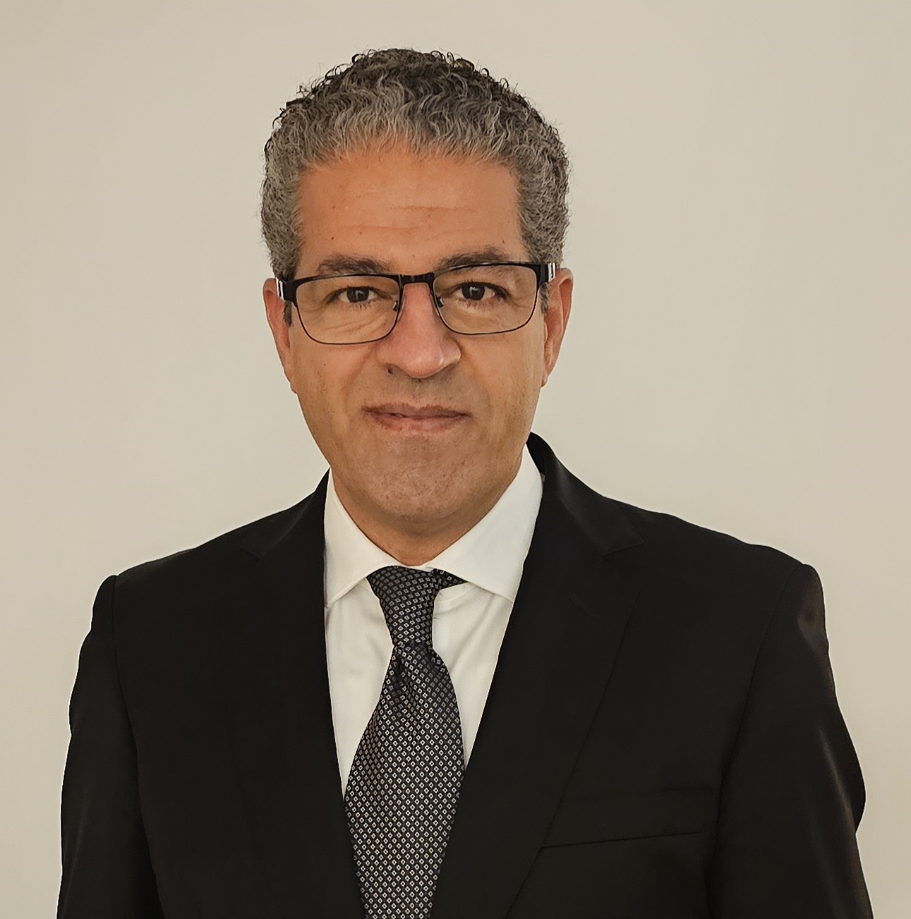 Smiling gentleman with glasses, grey tie and black suit
