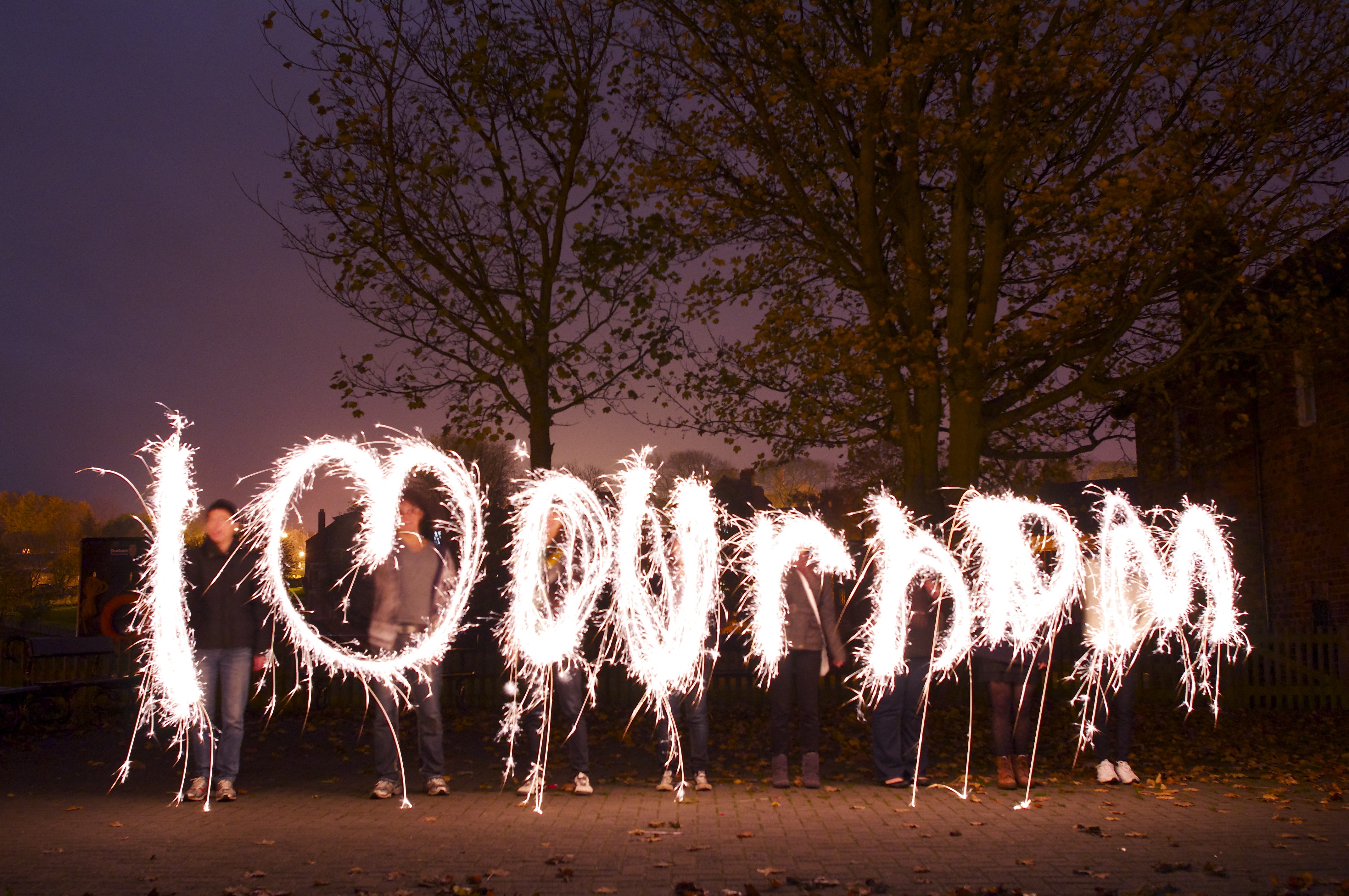 A picture of people drawing letters with sparklers to spell a word