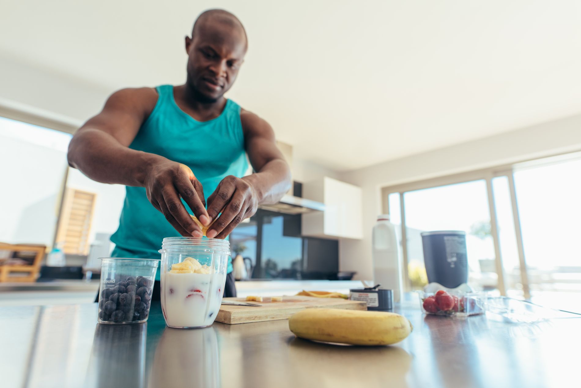 Man breaking up fruit into a blender to make a smoothie drink.